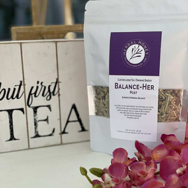 Tea package labeled 'Balance Her' with pink flowers on a white surface